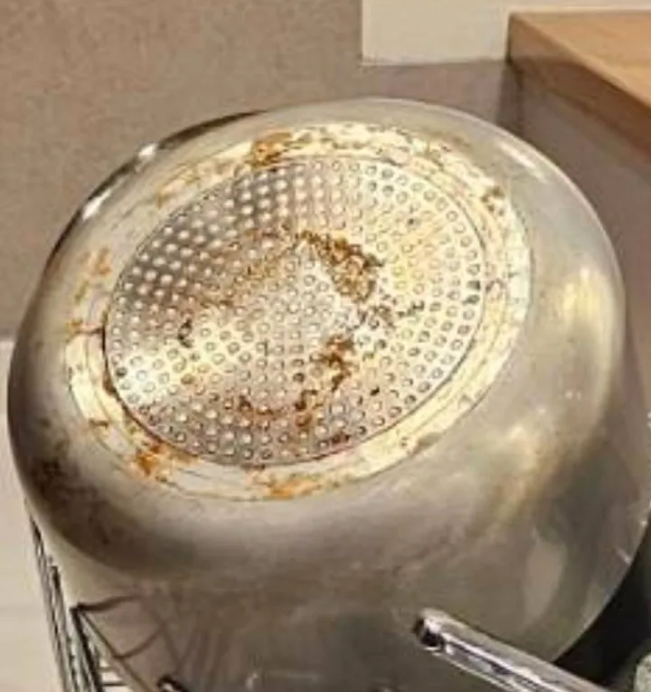 鍋底の清掃前。底面と縁に茶色い焦げ付きが残っている状態